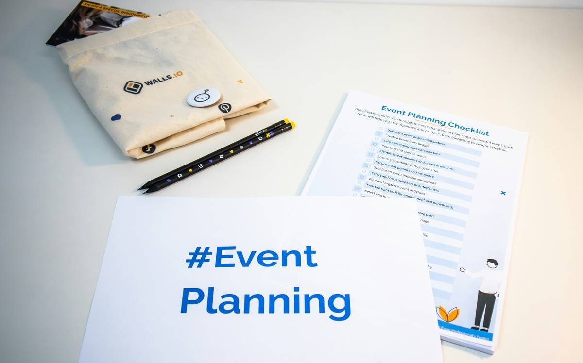 A desk with an event planning checklist, a piece of paper with the hashtag #EventPlanning and some branded merch