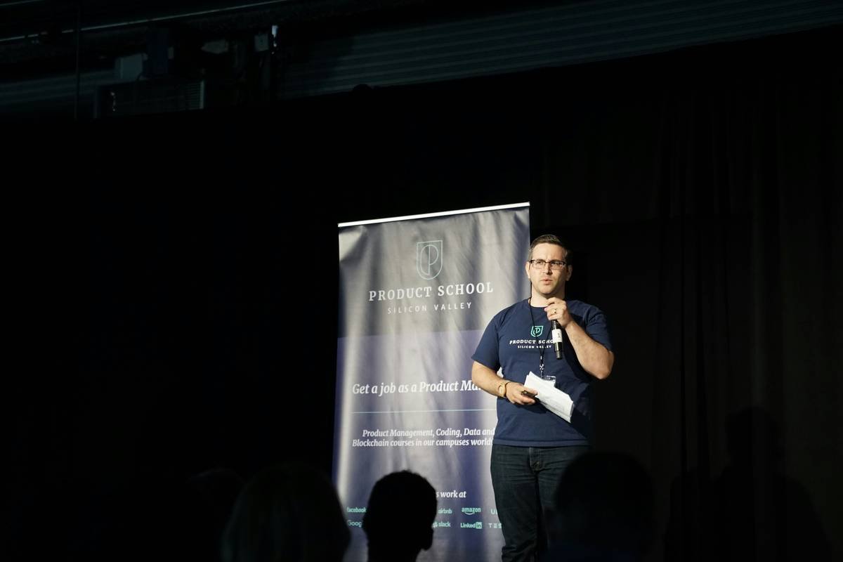 man on stage giving a presentation at a conference with an audience in the foreground