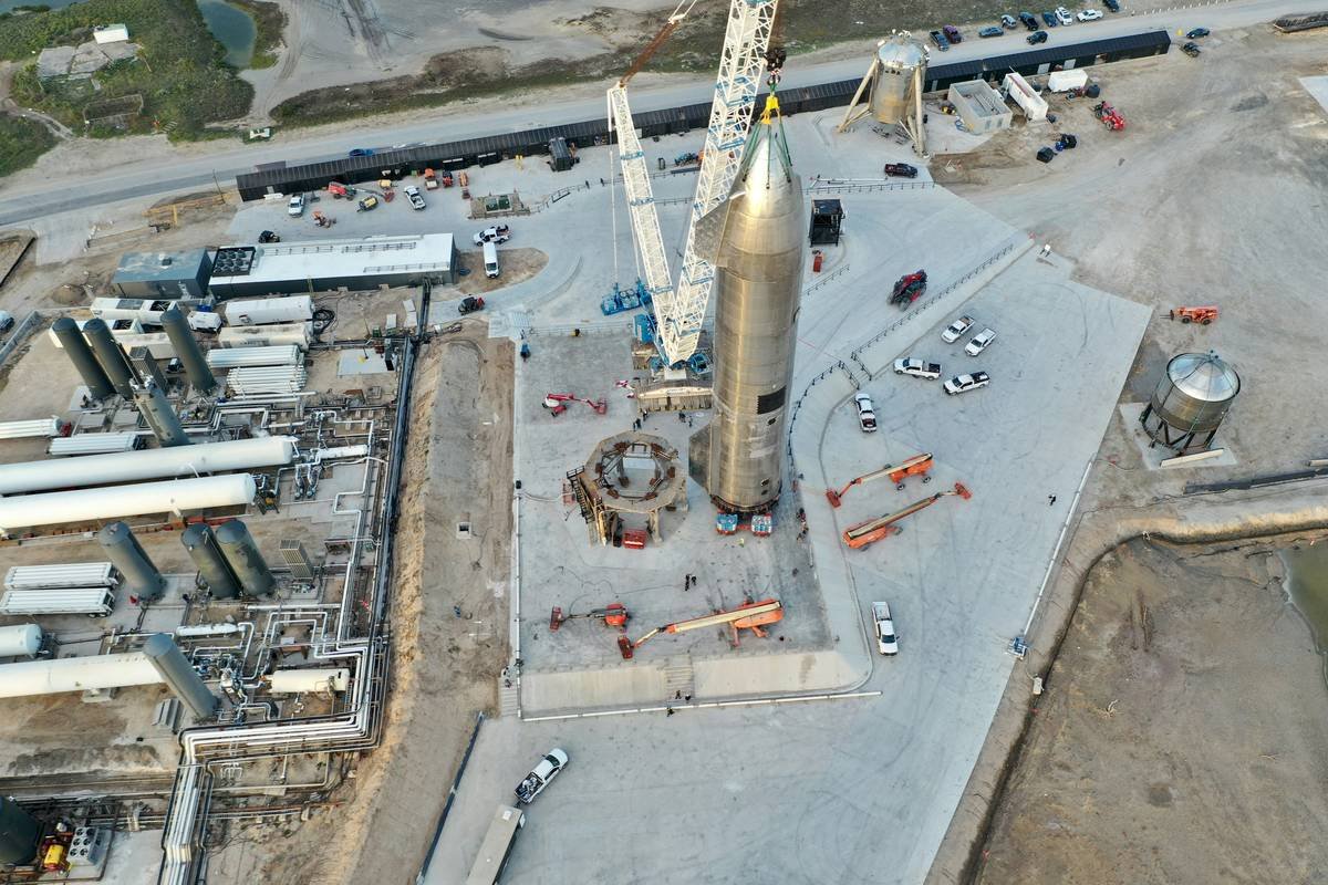 Rocket assembly at a launch facility with cranes and vehicles.